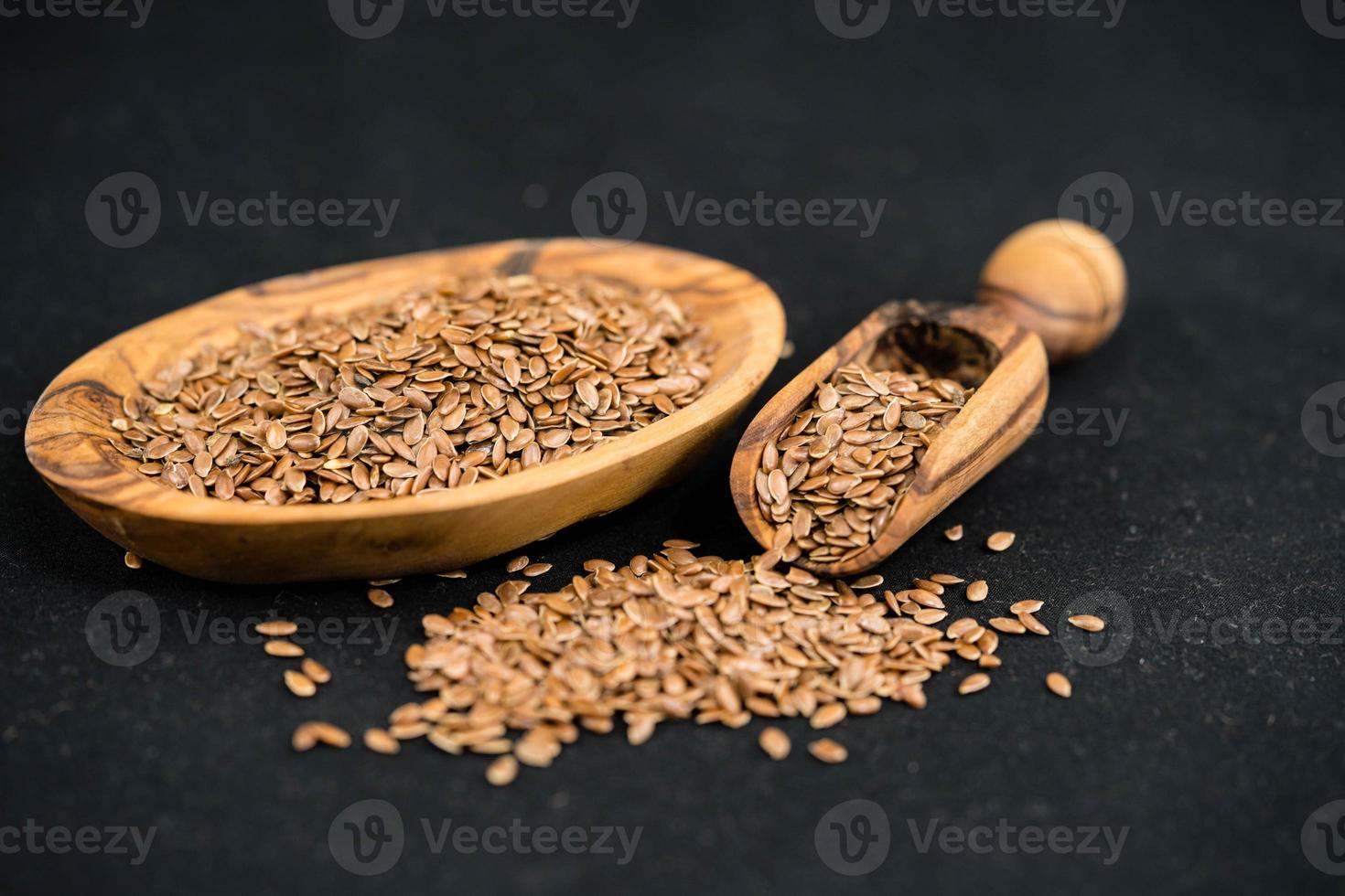 uma pilha de sementes de linhaça e utensílios feitos de madeira de oliveira foto