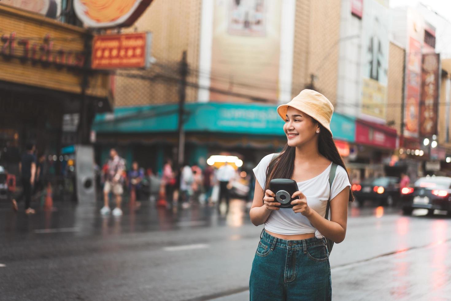 mulher jovem viajante asiática com câmera instantânea em bangkok, tailândia foto