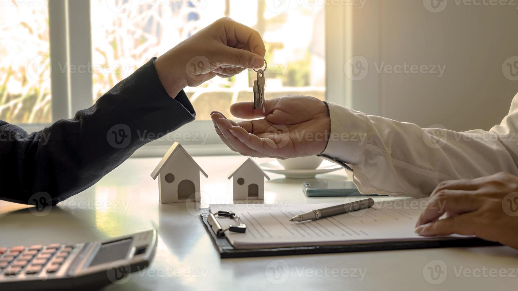 o agente imobiliário fornece as chaves da casa ao cliente após a assinatura do contrato imobiliário com um formulário de pedido de hipoteca aprovado. conceito de empréstimo hipotecário residencial e seguro residencial foto