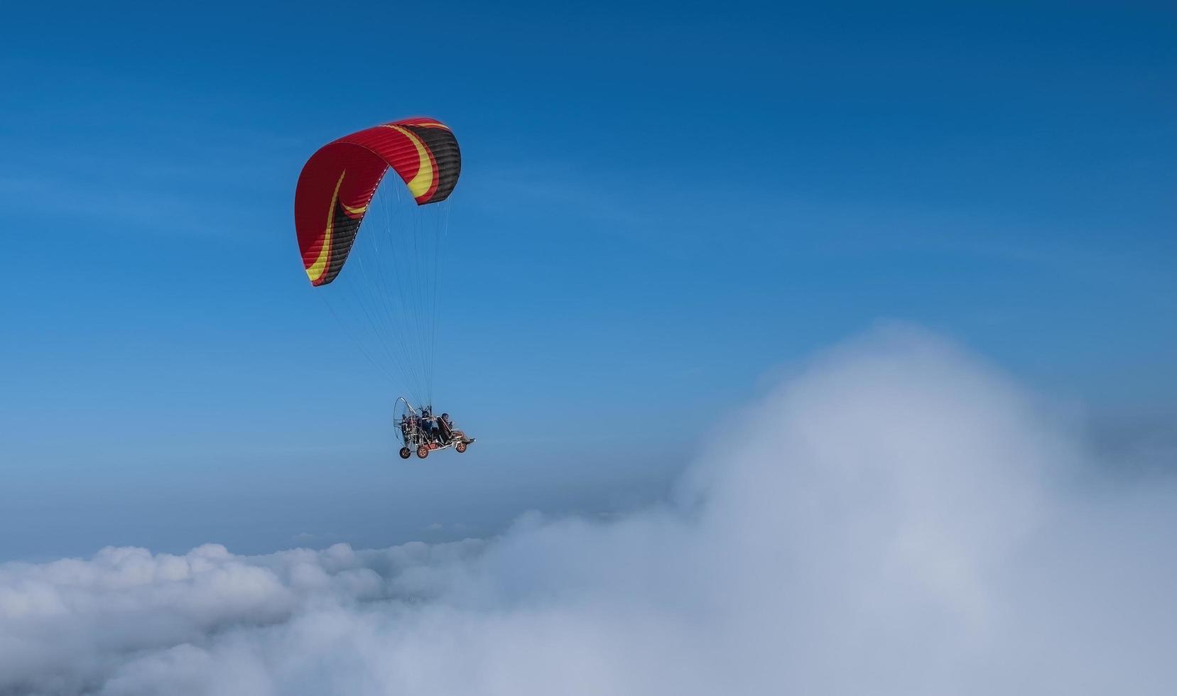 parapente voar sobre nuvem cpuffy com céu azul no fundo. conceito de liberdade. foto