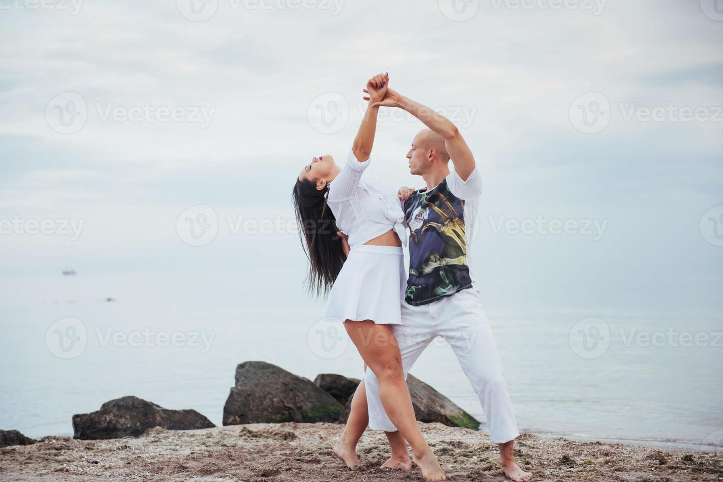 lindo casal dançando na praia ao fundo foto