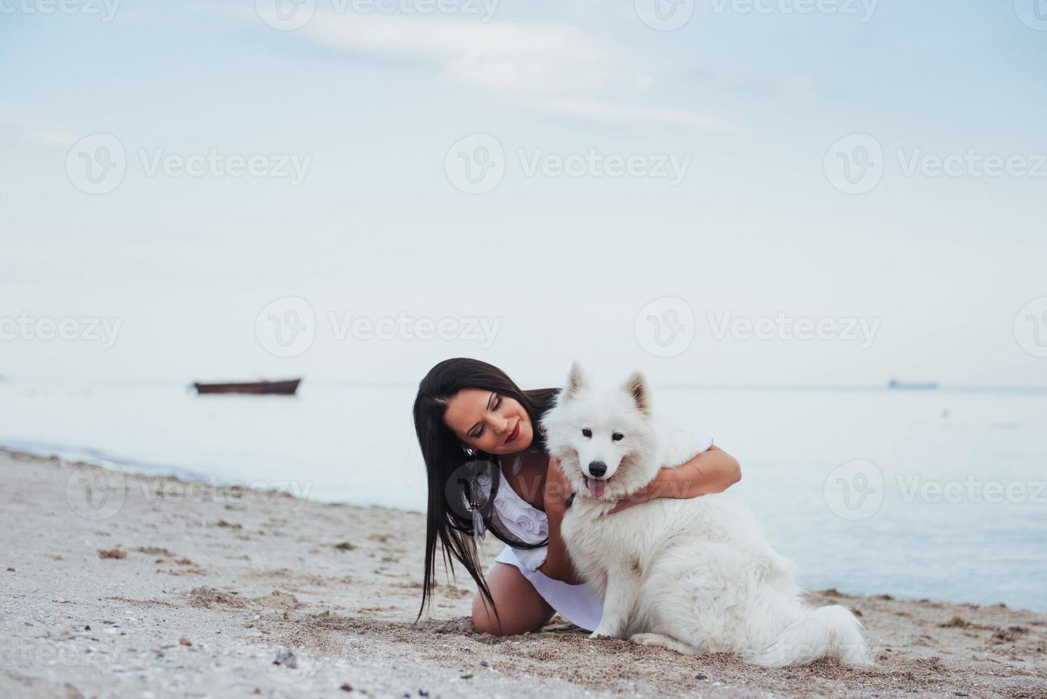mulher brincando com seu cachorro na praia foto