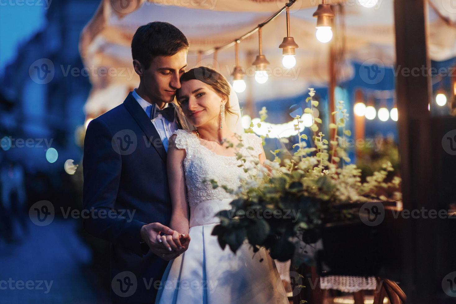 casal de noivos na iluminação noturna. café junto com decoração lig foto