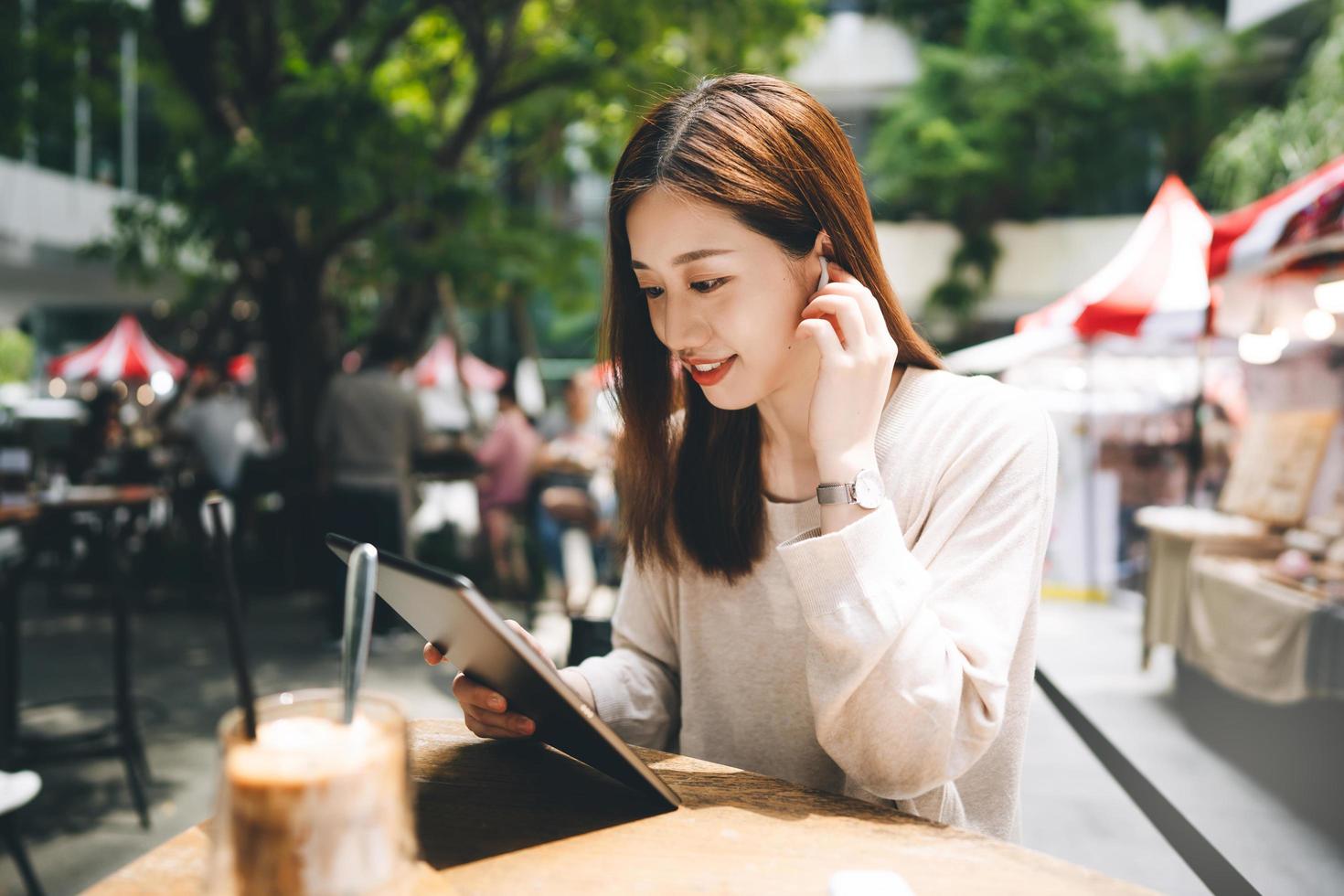 mulher asiática de negócios adulto jovem usa tablet para negócios no café de estilo de vida da cidade ao ar livre. foto