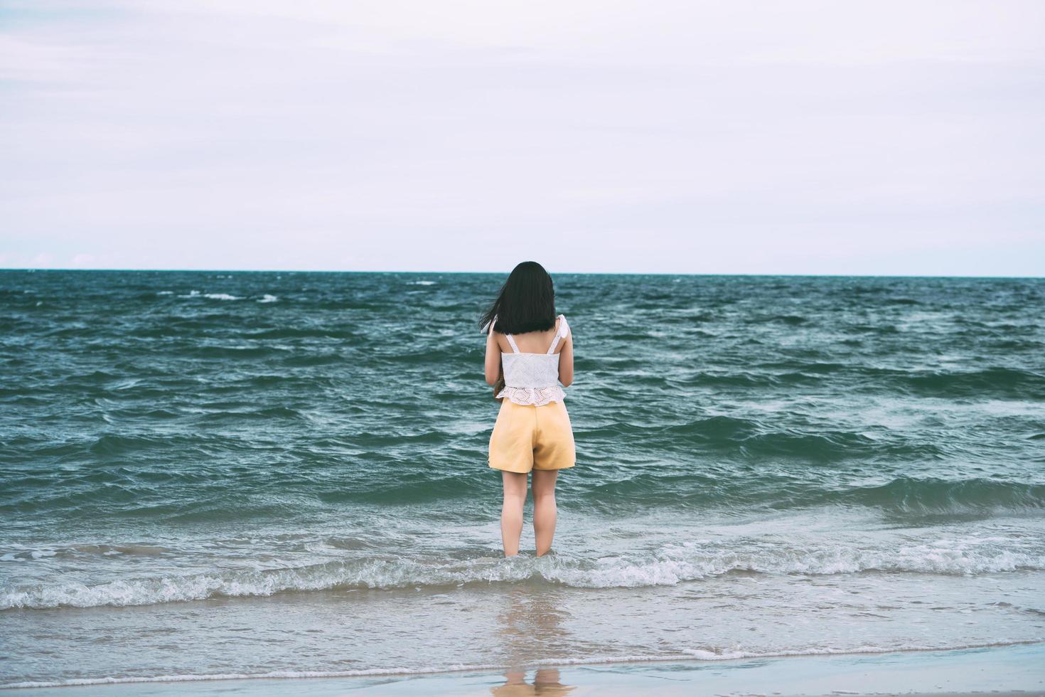 retrato de mulher asiática adulta jovem vista traseira relaxar na praia em dias. foto