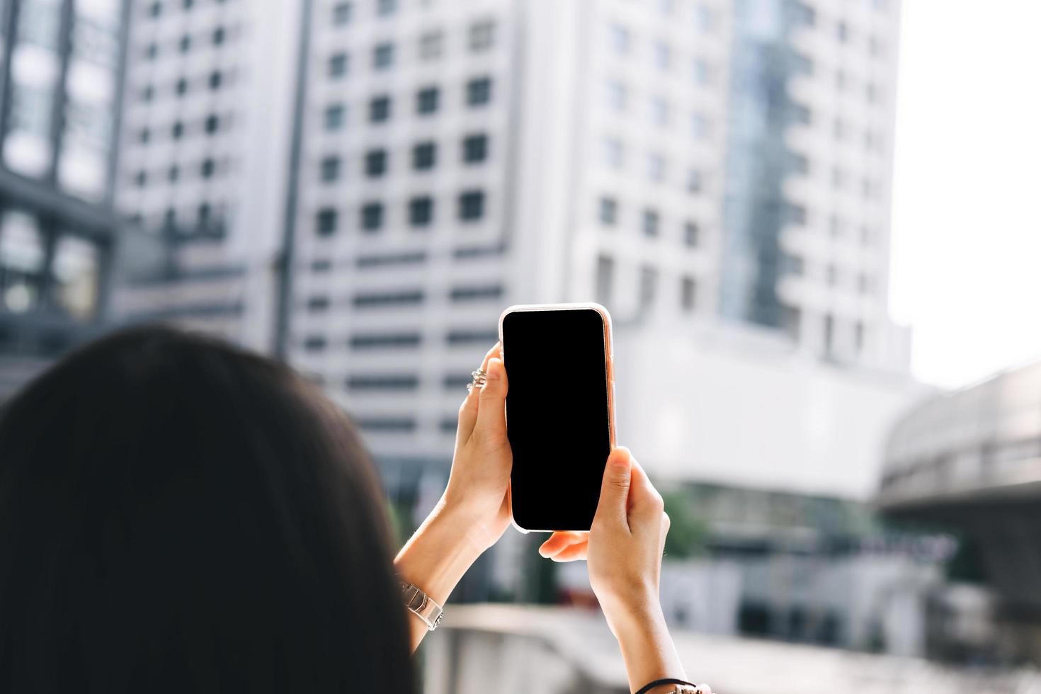 celular de tela preta em branco usando pela mão de mulher de negócios adulta vista traseira foto