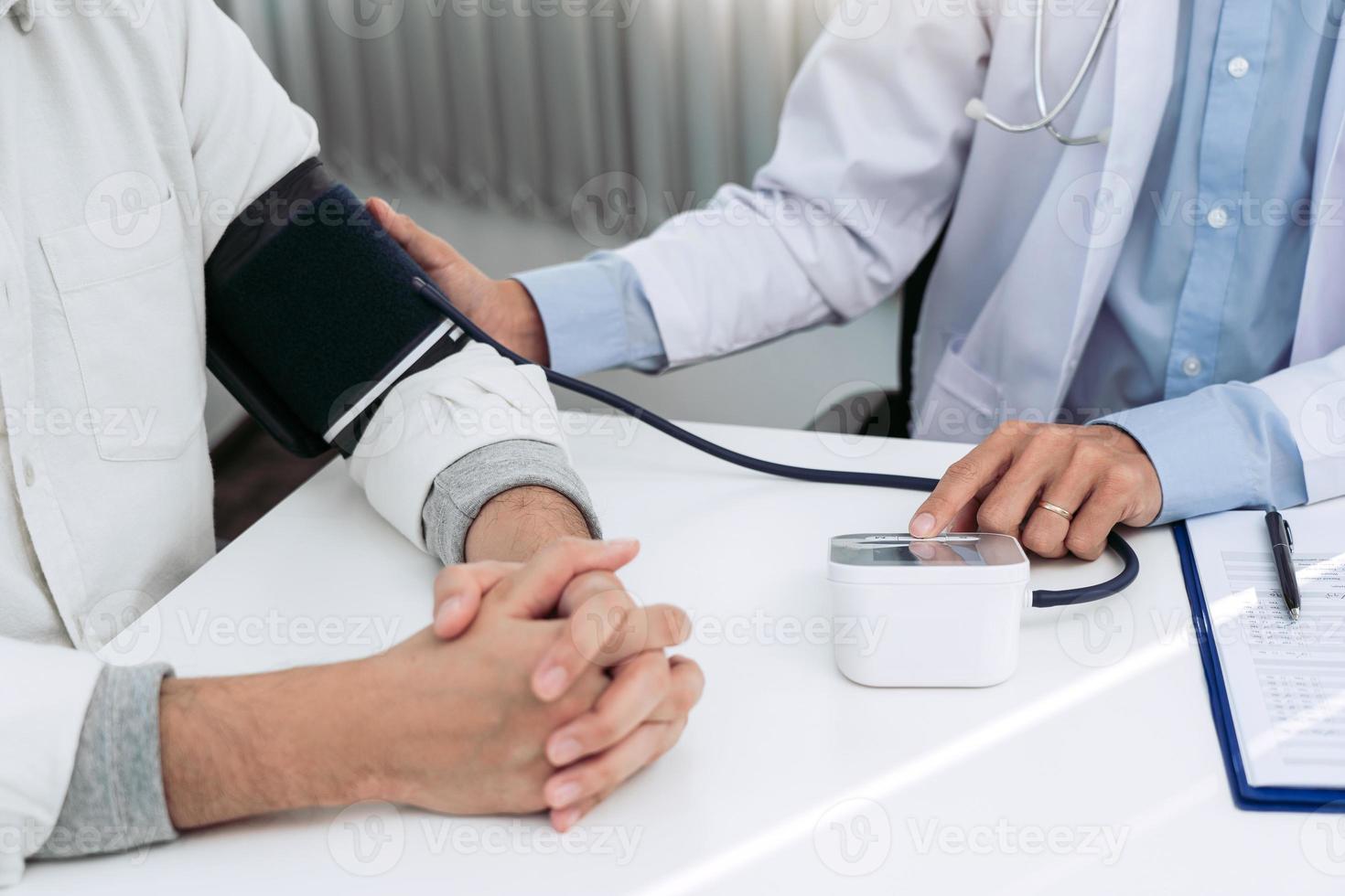 médico verificando a pressão arterial de um paciente sênior na sala do escritório. foto