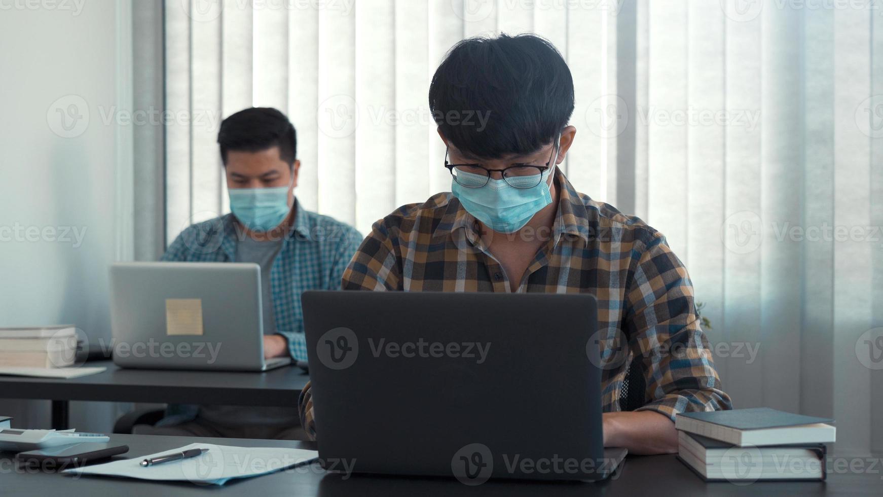 colega asiático trabalha usando uma máscara no escritório durante o covid-19. foto