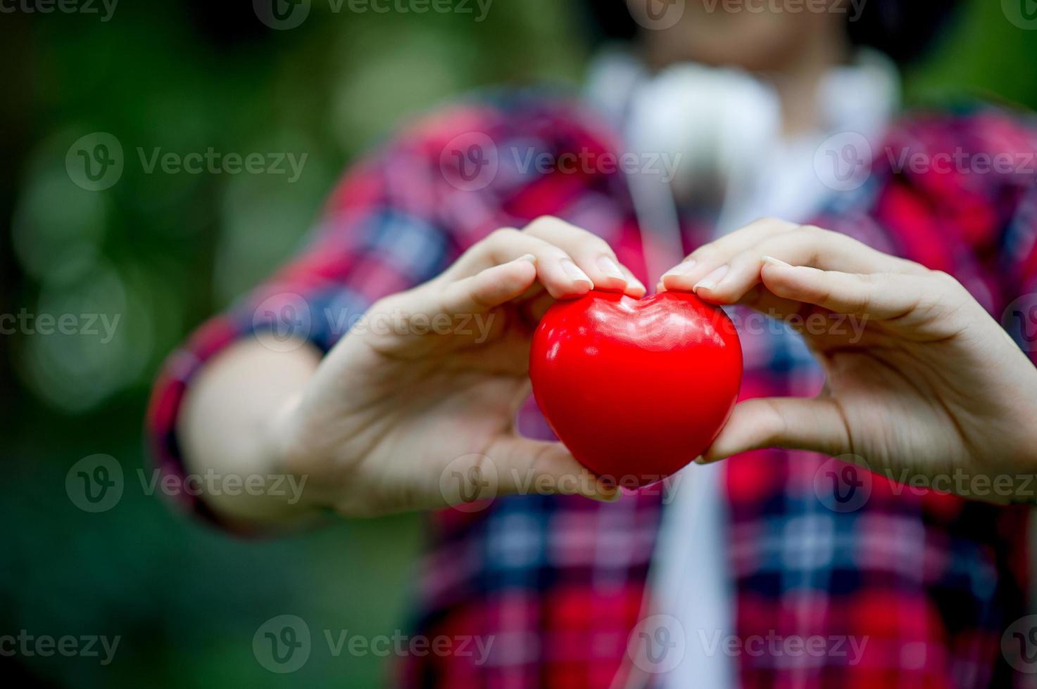 mão feminina e coração vermelho no espaço natural e espaço para cópia. foto