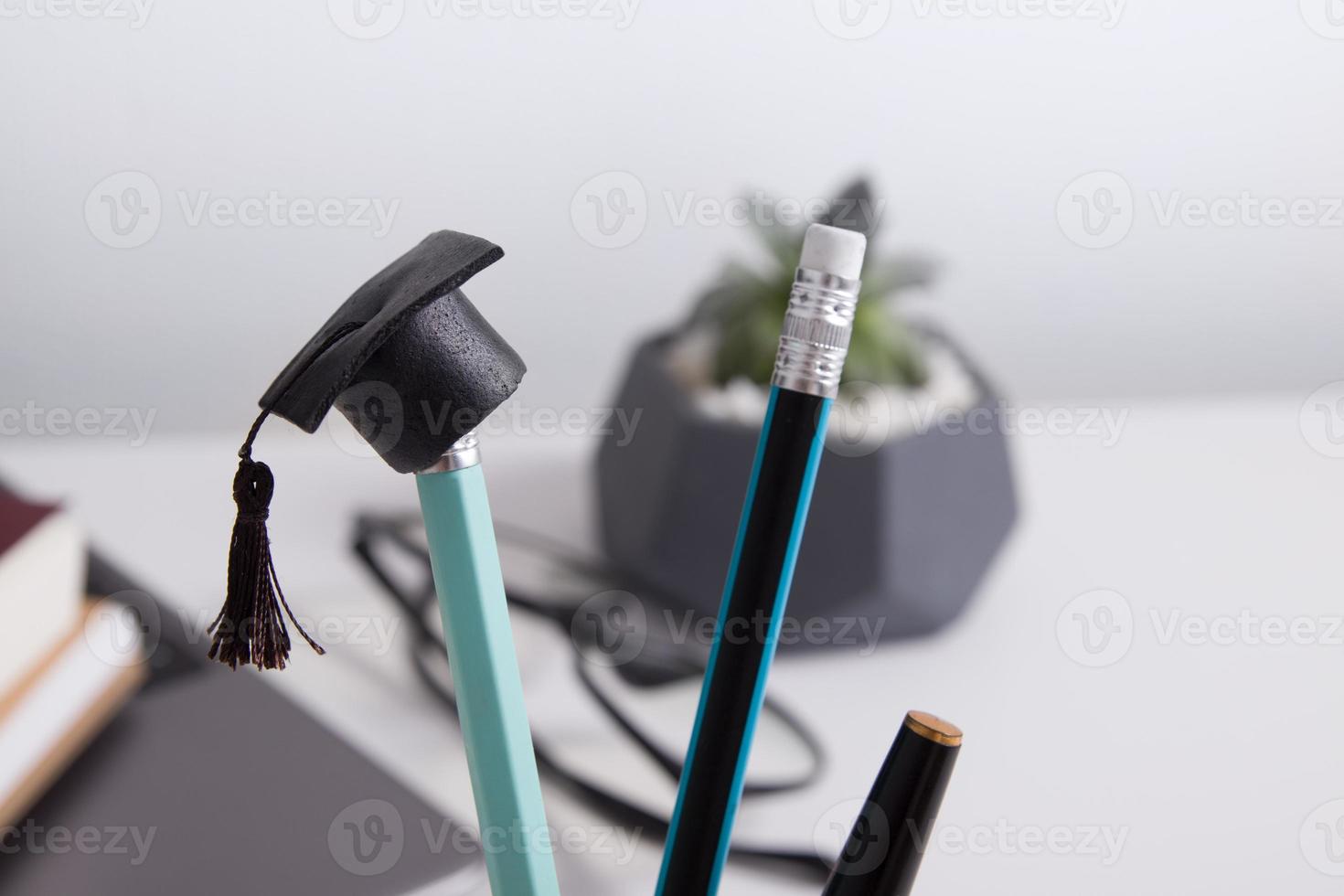 boné de pós-graduação em um lápis no fundo de uma área de trabalho com artigos de papelaria. conceito de homeschooling durante uma pandemia foto