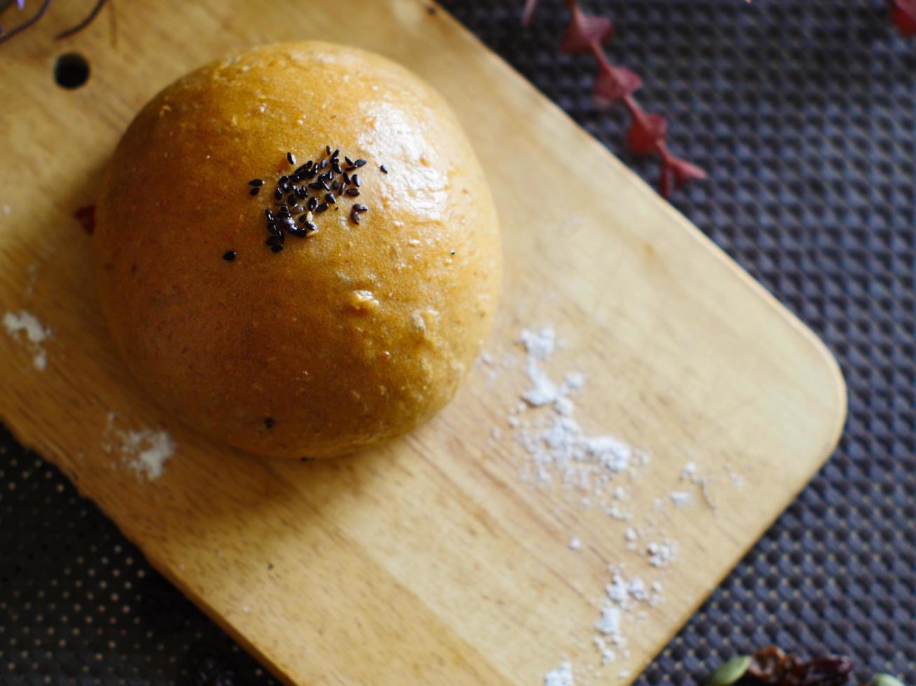 pão integral polvilhado com sementes de gergelim preto, colocado sobre uma tábua de madeira, polvilhado com açúcar de confeiteiro. imagem de comida de padaria foto