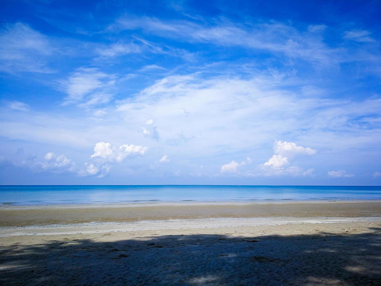o céu azul brilhante e as nuvens brancas brilhantes, a praia e o mar azul claro durante o dia foto