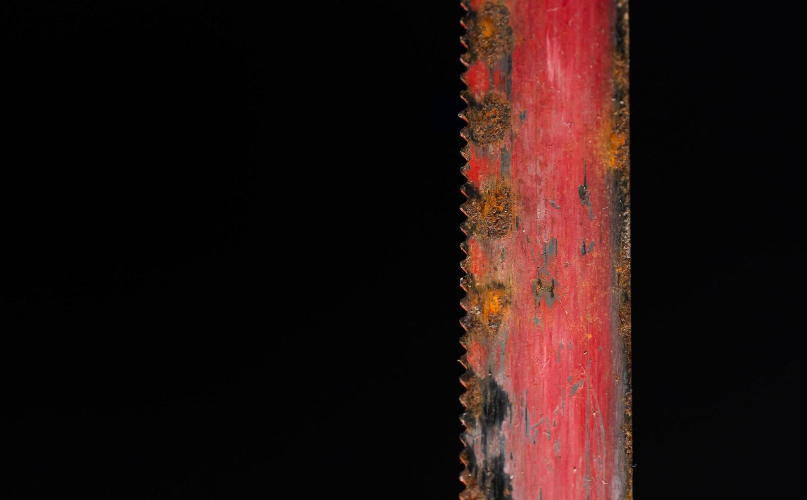 lâmina de serra vermelha velha desgastada com ferrugem na superfície e arranhões. foto macro em fundo preto.