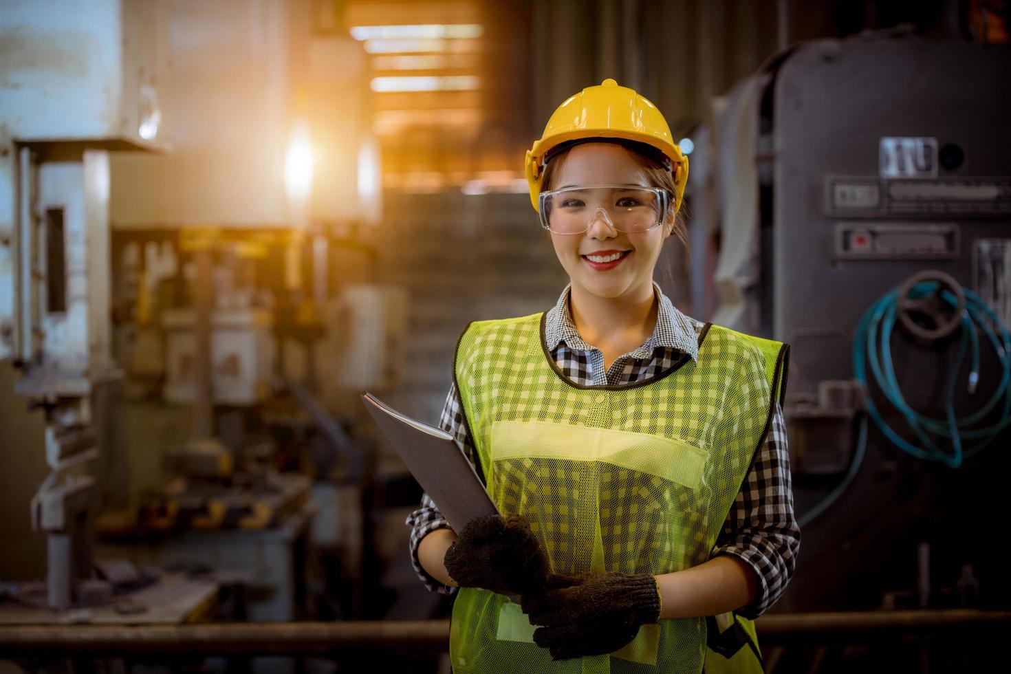 mulher trabalhadora da indústria sob inspeção e verificação do processo de produção na estação de fábrica por laptop na mão, trabalhador vestindo uniforme casual e capacete de segurança no trabalho foto