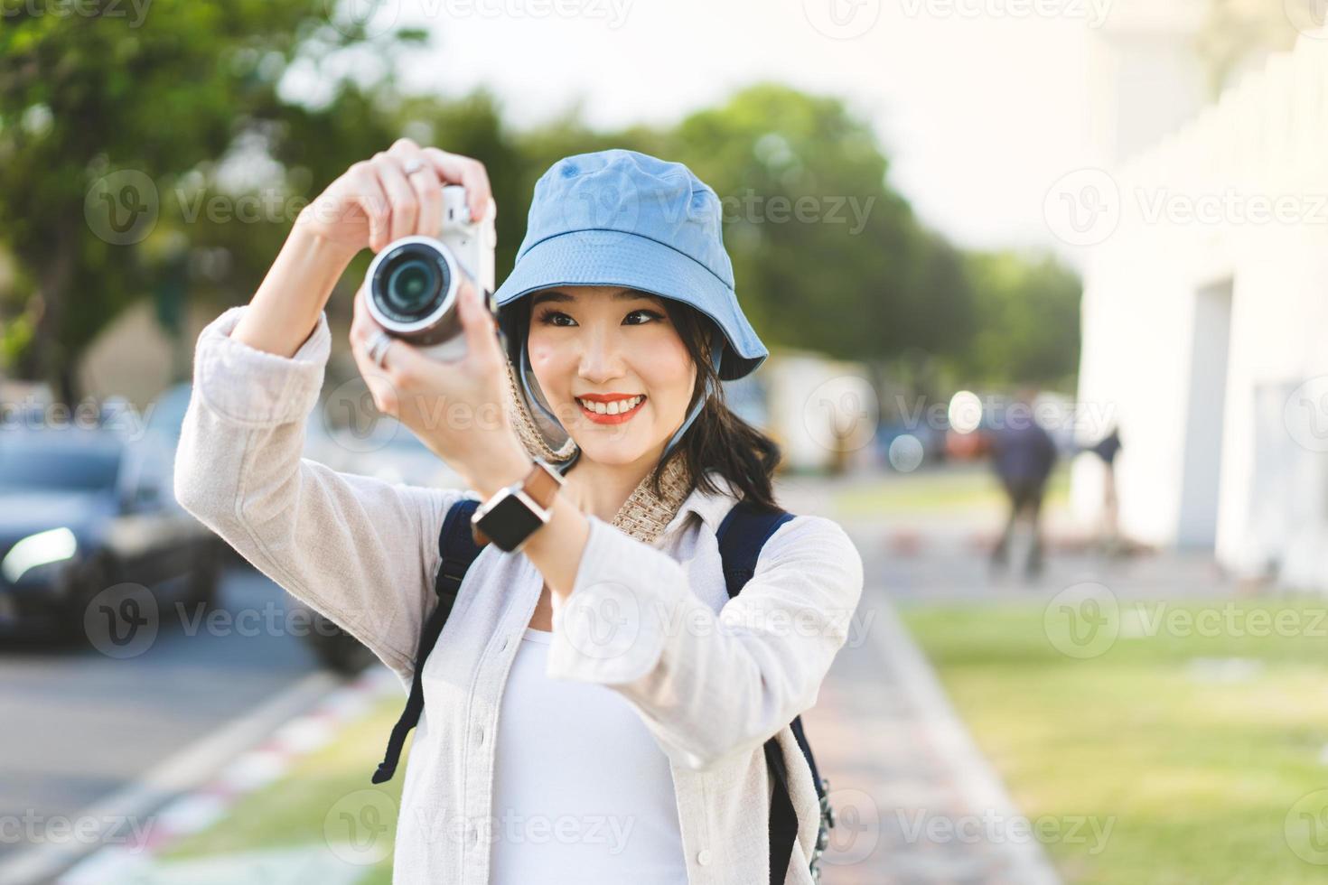 viajante de mulher asiática adulta jovem atraente usando a câmera para viagem de fotos. foto