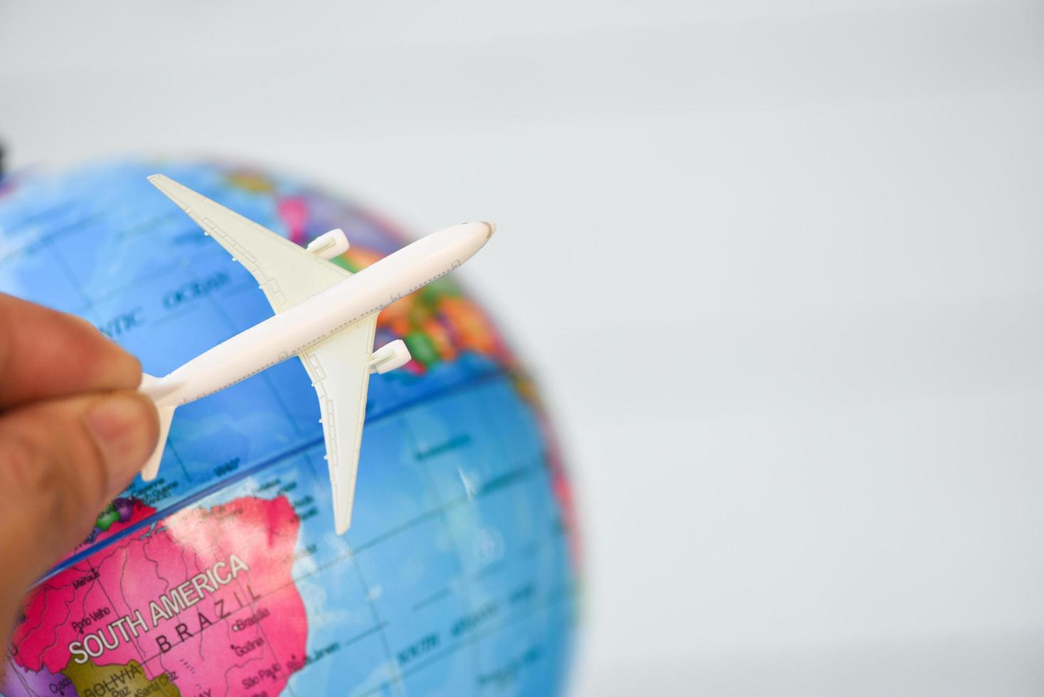 homem de negócios, segurando o avião de avião no fundo do globo do mundo - conceito de viagens em todo o mundo foto