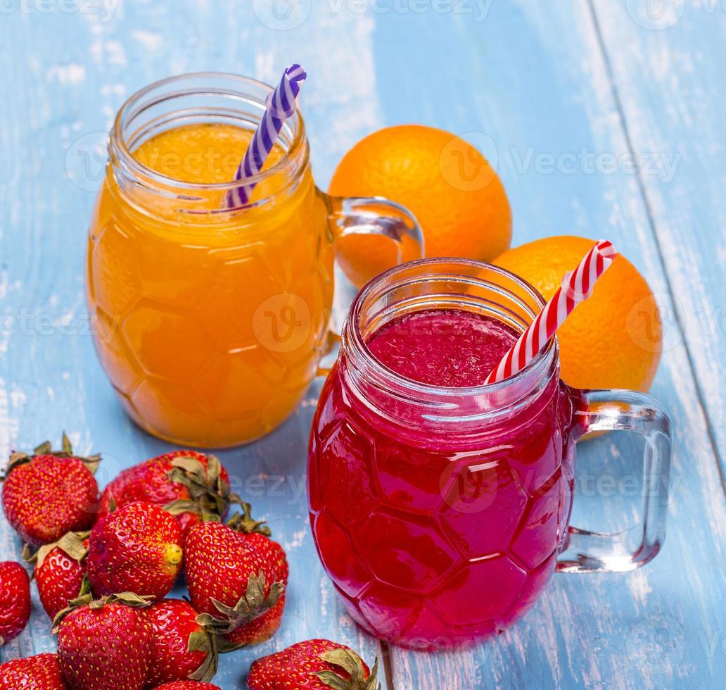 coquetéis de morango e laranja frescos com frutas em um fundo rústico de madeira. foto