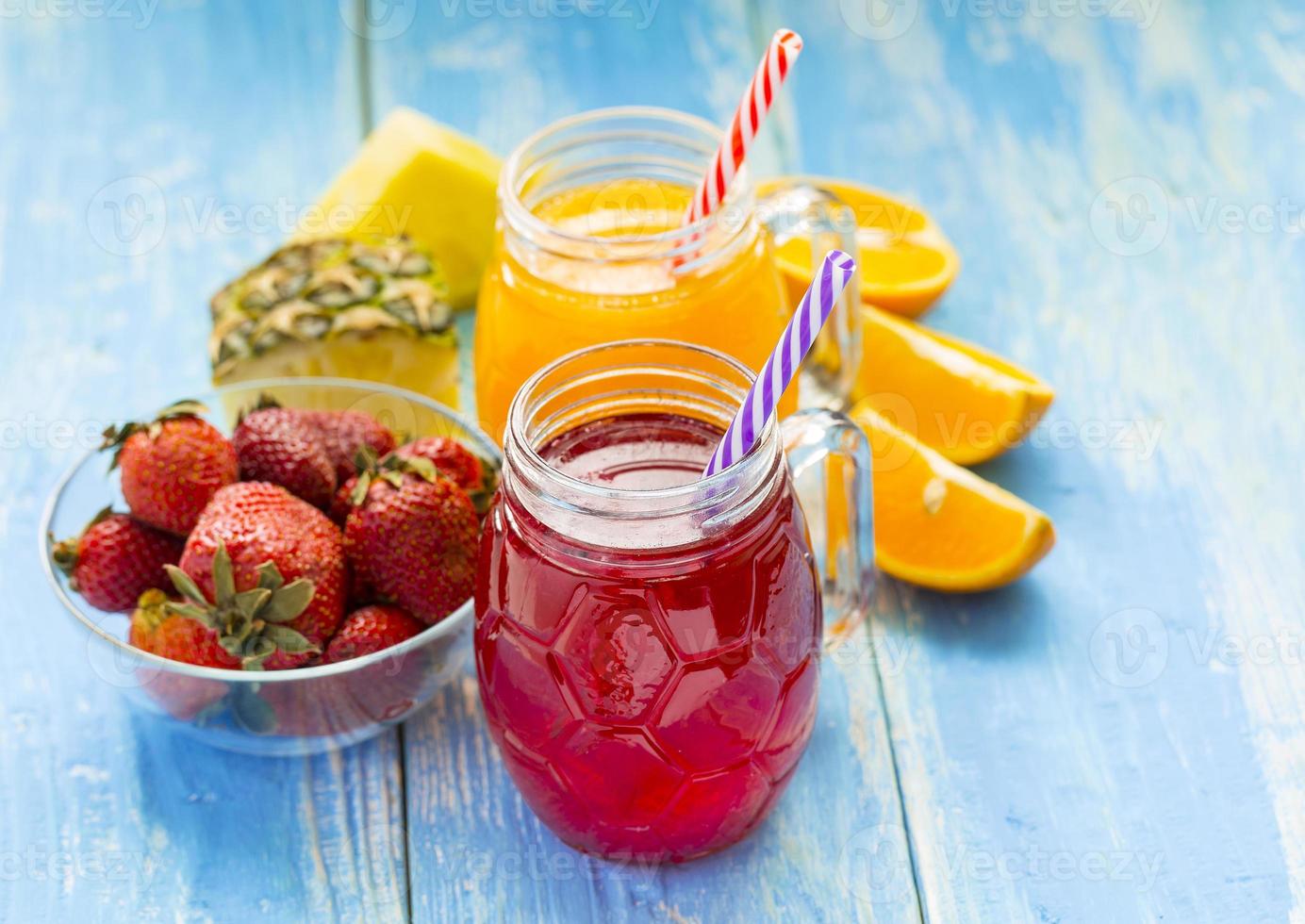 smoothie de abacaxi e morango fresco em copos com frutas em um fundo rústico de madeira azul foto