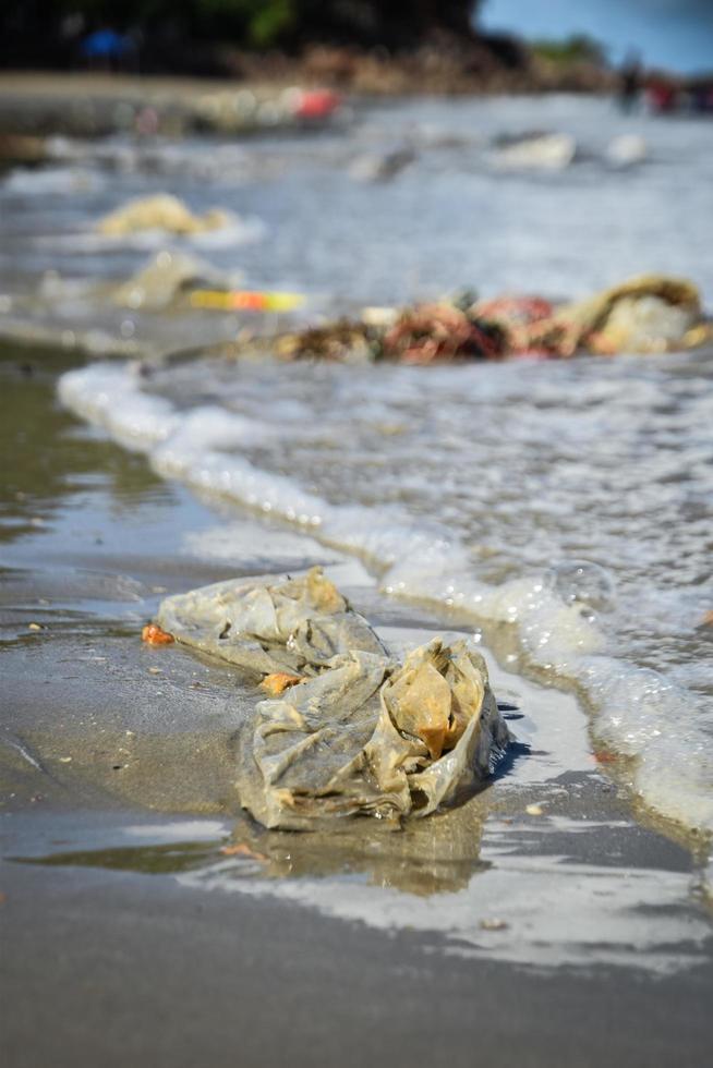 poluições e lixos na praia de pessoas foto