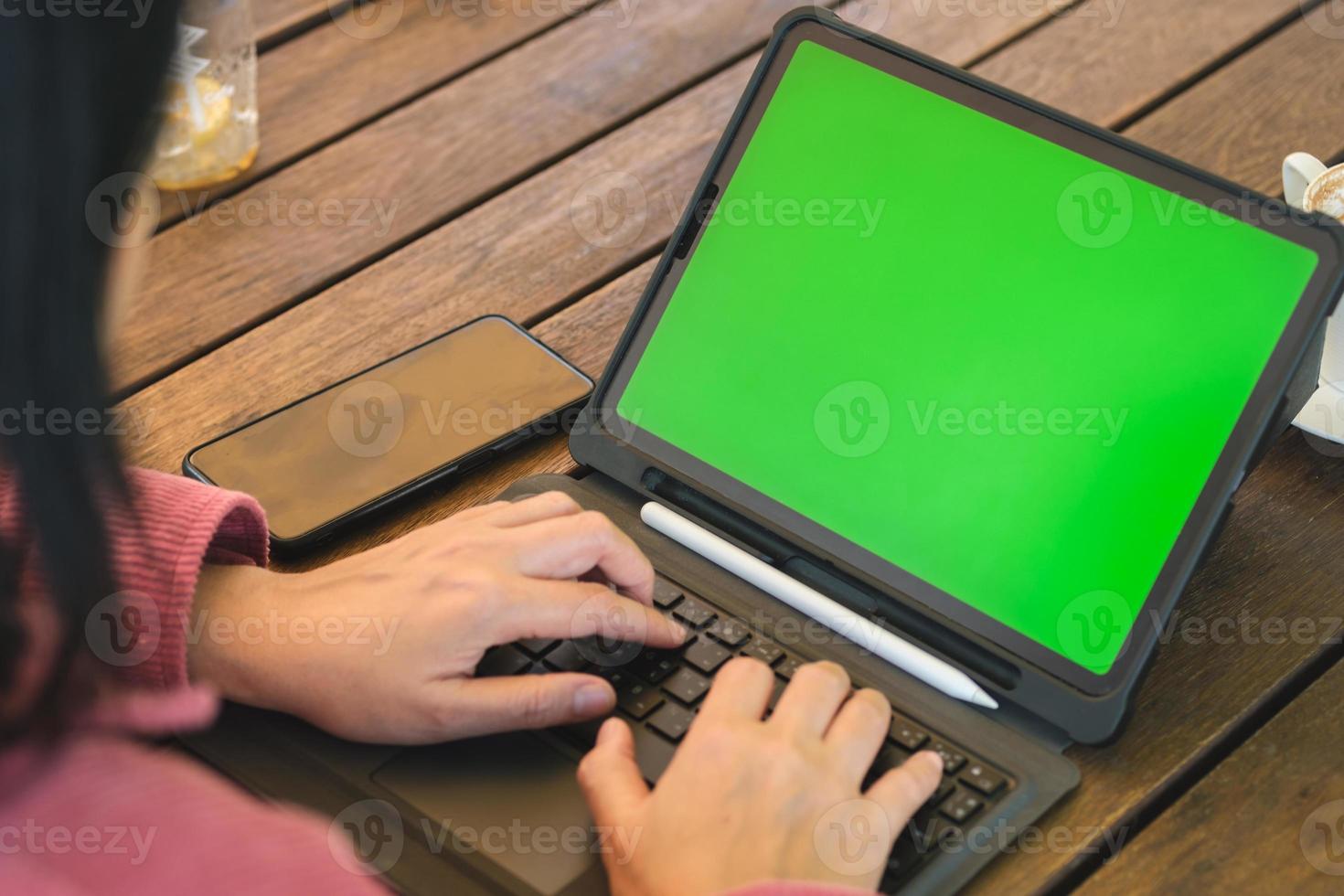 mulher asiática trabalhando com tela verde tablet online no café foto