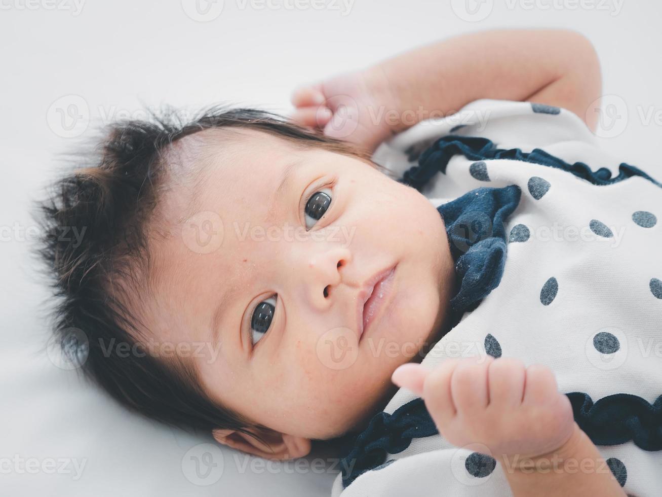 retrato de três semanas bebê recém-nascido asiático australiano ou criança deitada na cama branca e abrindo os olhos. foto