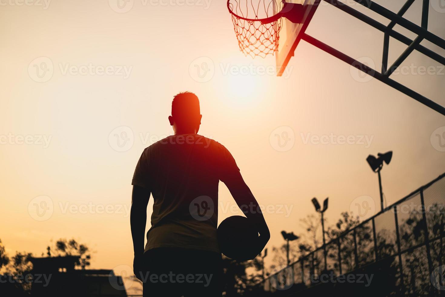 silhueta de jogador de basquete ao pôr do sol. jogador de basquete atira um tiro. conceito de basquete esportivo. foto