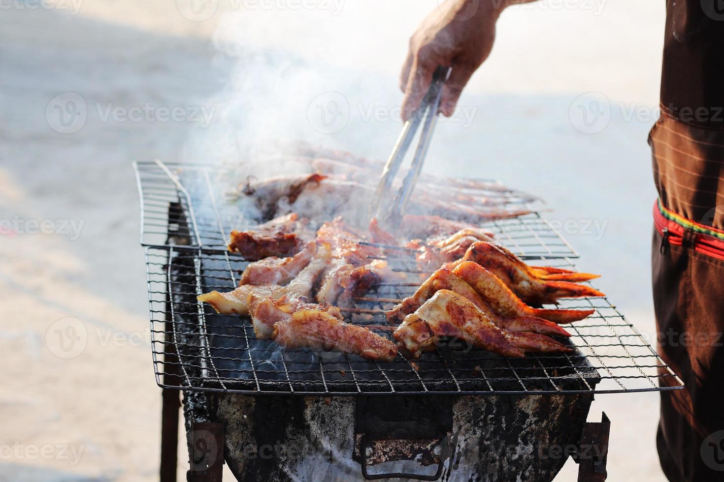 foco seletivo de carne de porco grelhada e frango em uma grelha de comida de rua. foto