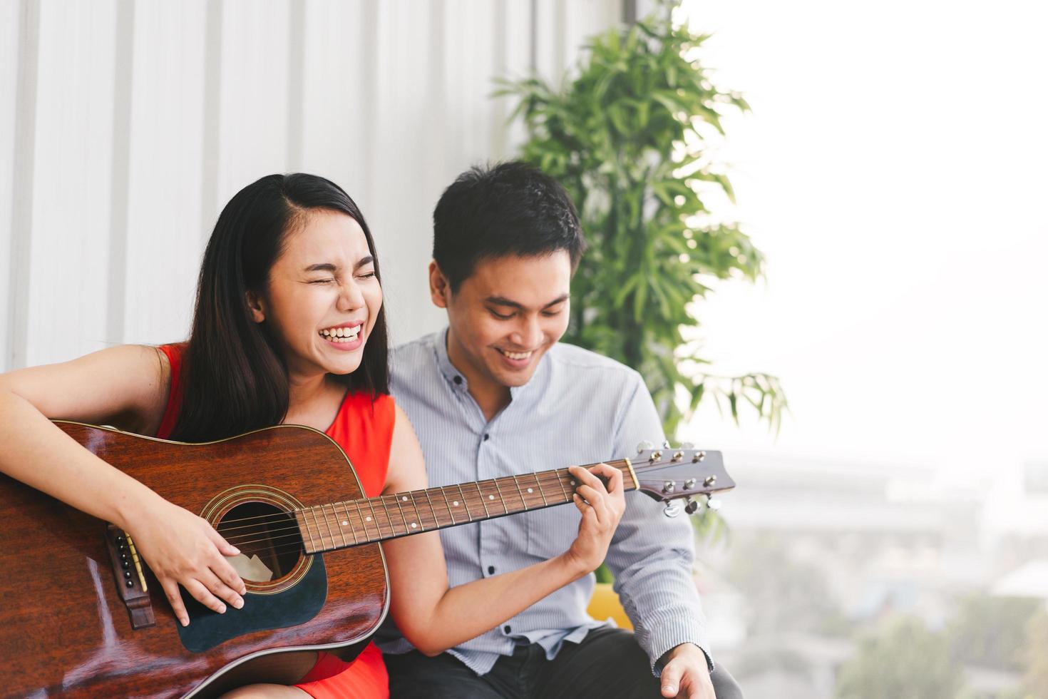 adorável jovem casal asiático adulto tocando violão juntos foto