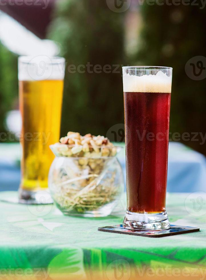 cerveja clara e escura com petiscos na mesa no terraço do bar ao ar livre foto
