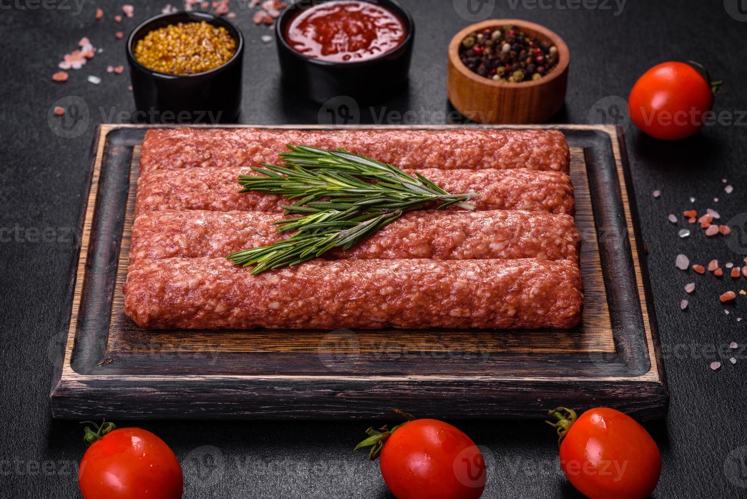 carne moída crua fresca para kebab grelhado com especiarias e ervas em um fundo escuro de concreto foto