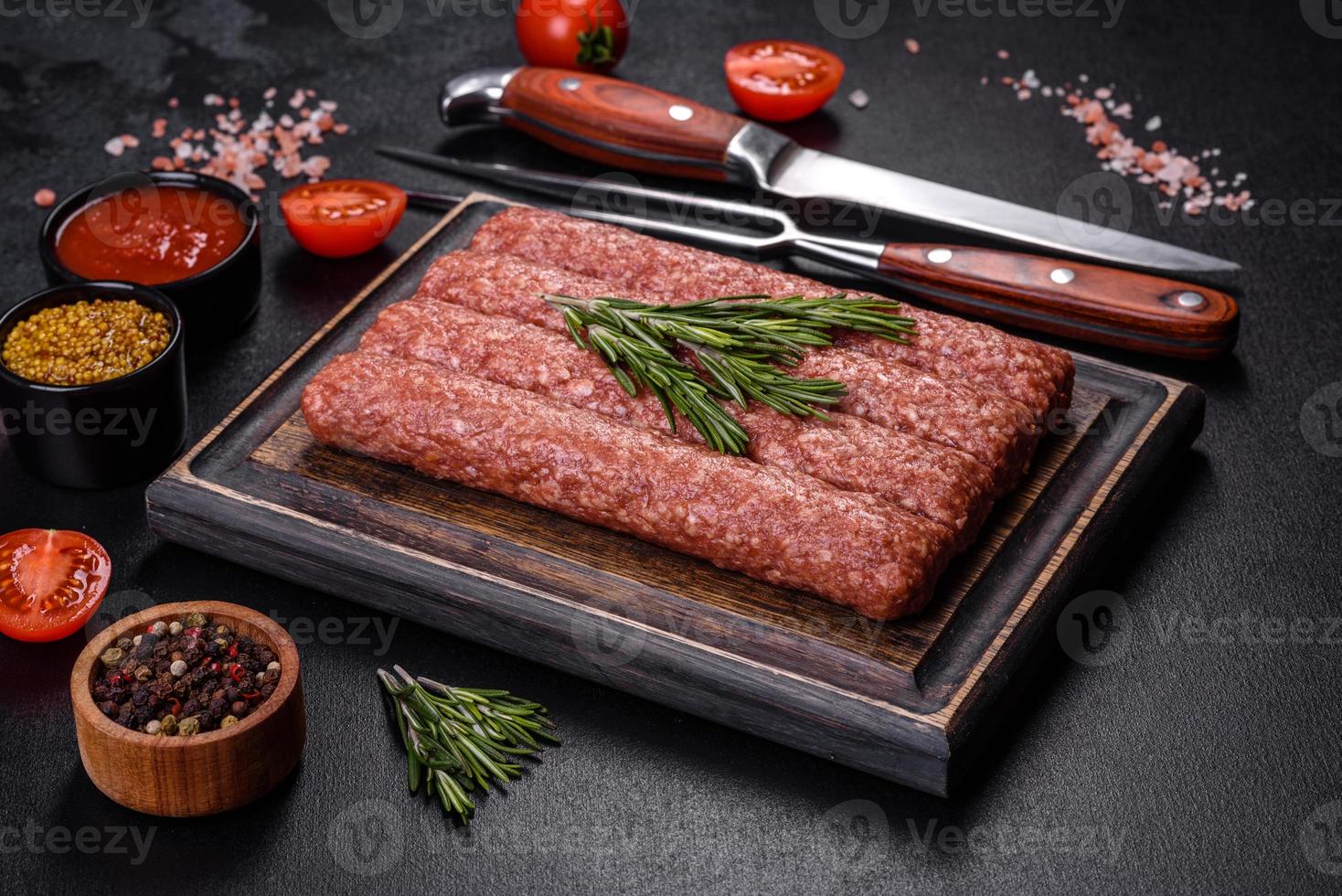 carne moída crua fresca para kebab grelhado com especiarias e ervas em um fundo escuro de concreto foto