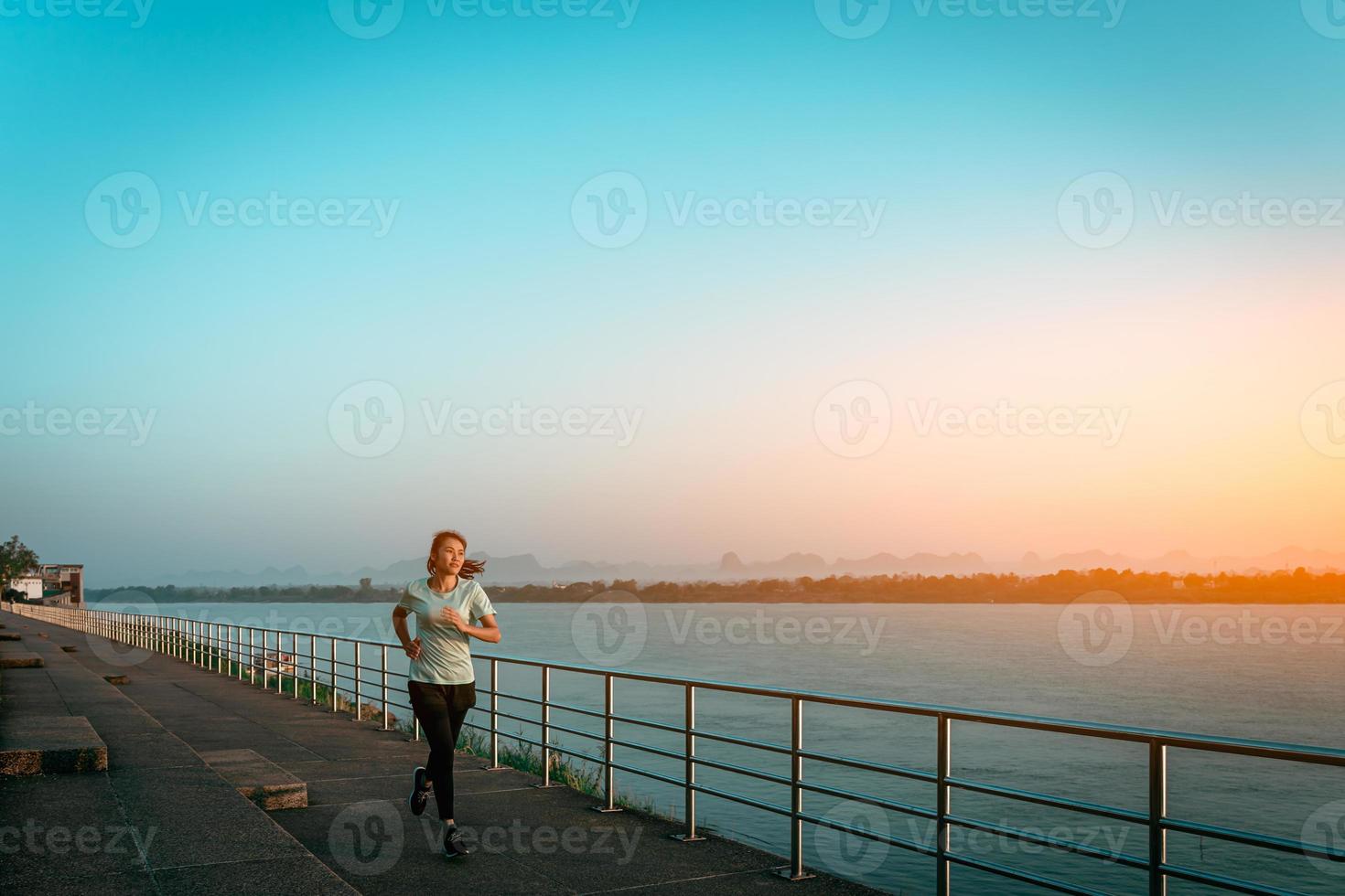 mulher correndo na rua com vista para o rio pela manhã. foto