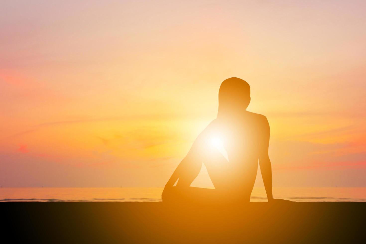 silhueta de jovem com traçado de recorte praticando ioga relaxante exercício ao pôr do sol foto