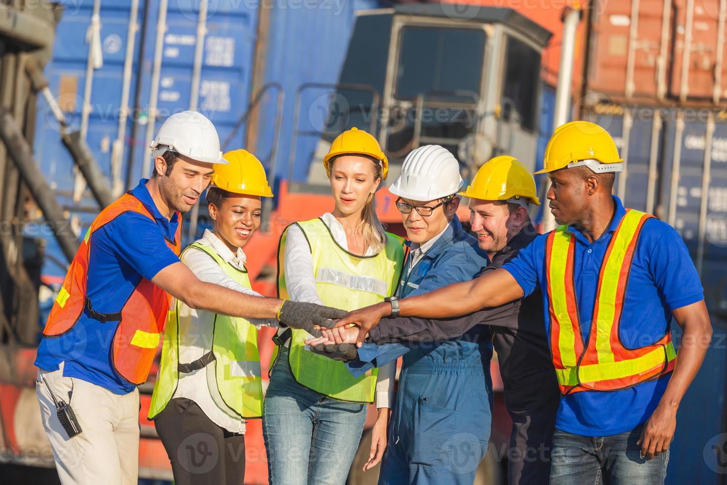 conceito de trabalho em equipe de sucesso e felicidade, grupo de empresários, equipe de engenheiros e trabalhadores juntando as mãos com fundo de contêineres de carga turva foto