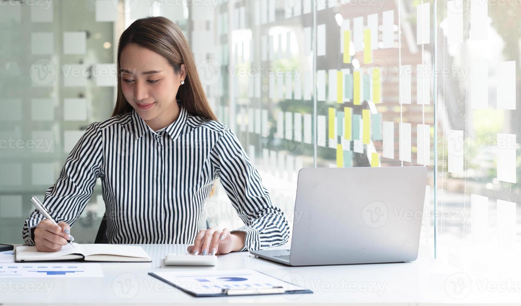 mulher de negócios usando a calculadora para fazer finanças matemáticas na mesa de madeira no escritório e no plano de trabalho de negócios, impostos, contabilidade, estatísticas e conceito de pesquisa analítica foto