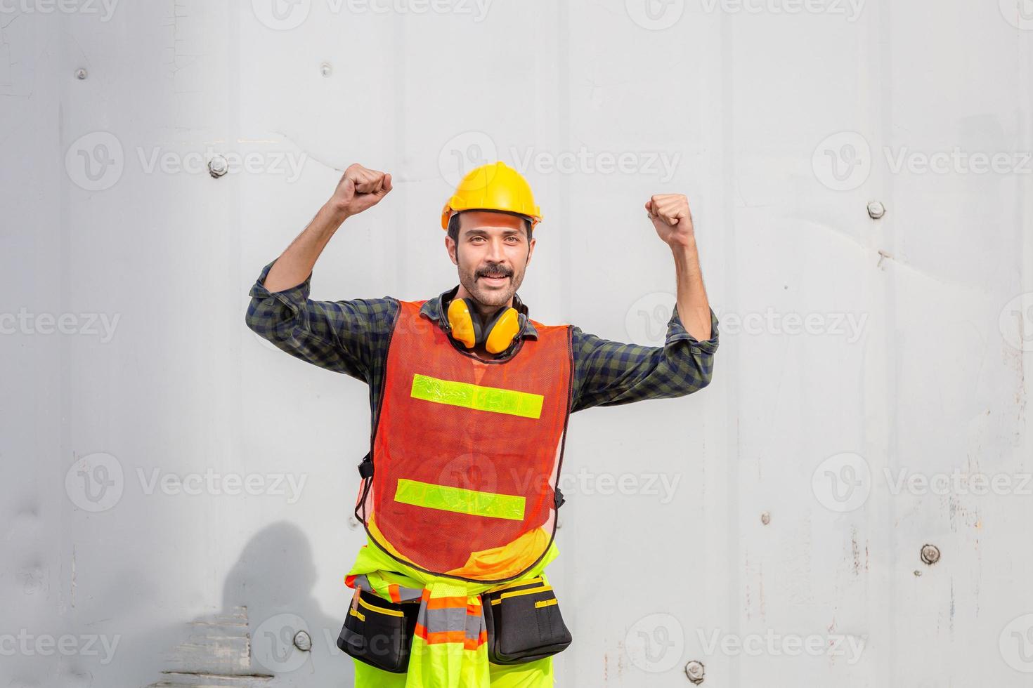 engenheiro homem no capacete de segurança e colete de segurança comemorando a vitória no canteiro de obras foto