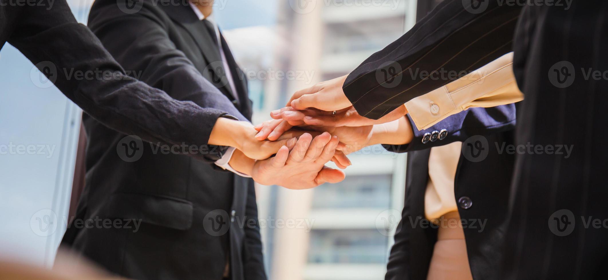 conceito de sucesso e trabalho em equipe, equipe de empresários juntando as mãos após a reunião no escritório moderno foto