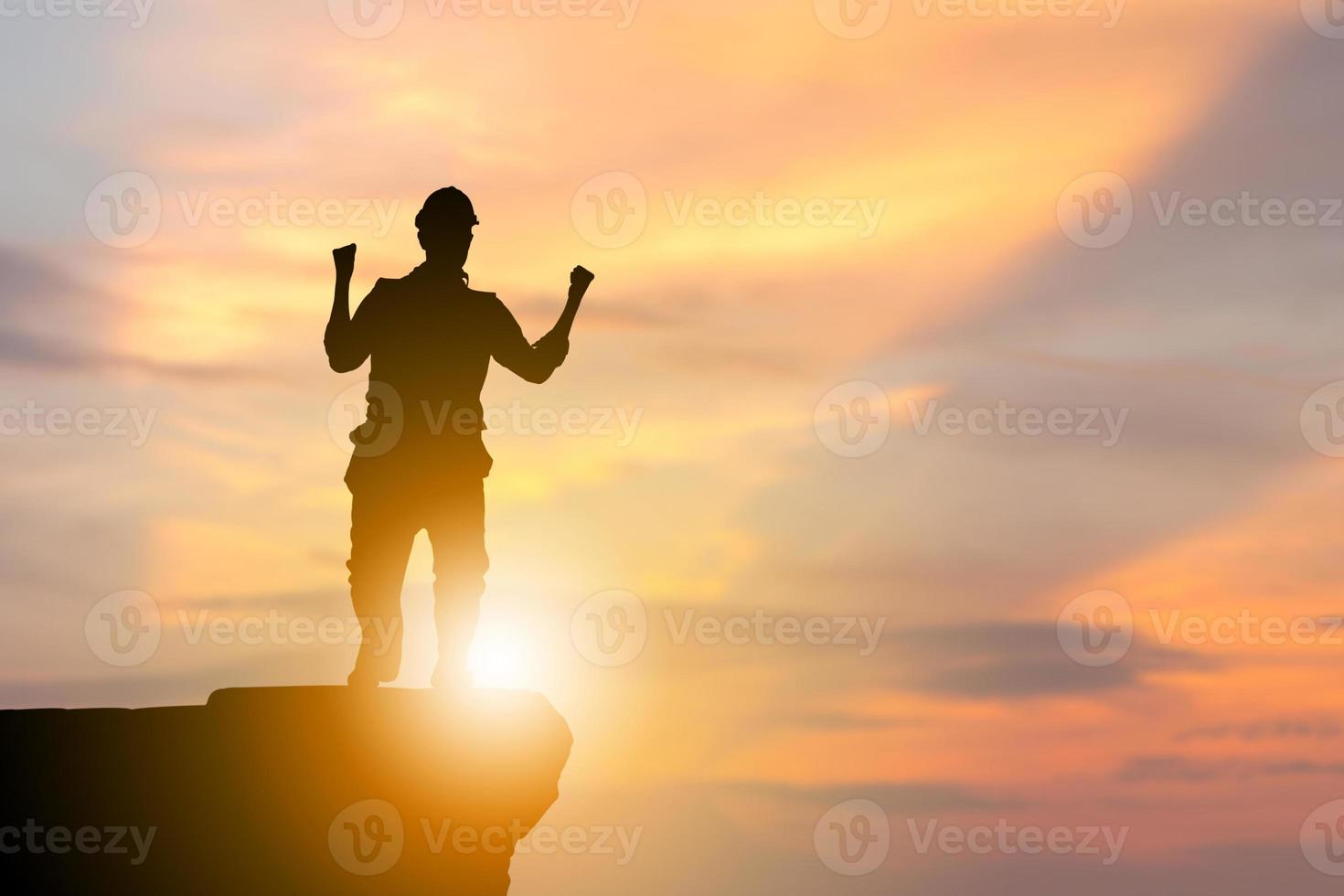 silhueta de homem engenheiro com traçado de recorte comemorando a vitória no fundo do pôr do sol do céu à noite de pedra, conceitos de sucesso foto