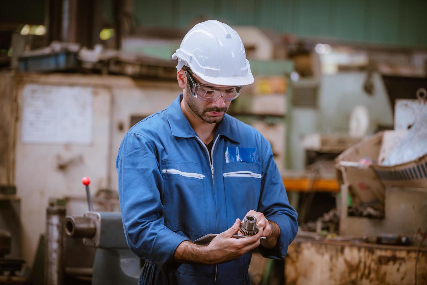 engenharia da indústria vestindo controle uniforme de segurança operando máquina de moagem de torno controlada por computador trabalhando na fábrica da indústria. foto