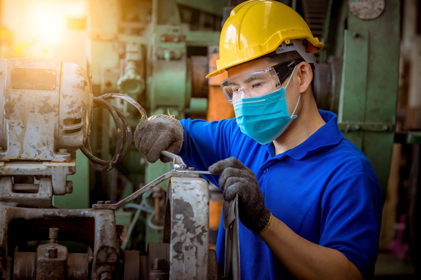 engenheiro sob inspeção e verificando o processo de produção na estação de fábrica segurando a chave de fenda usando máscara de segurança para proteger contra poluição e vírus na fábrica. foto