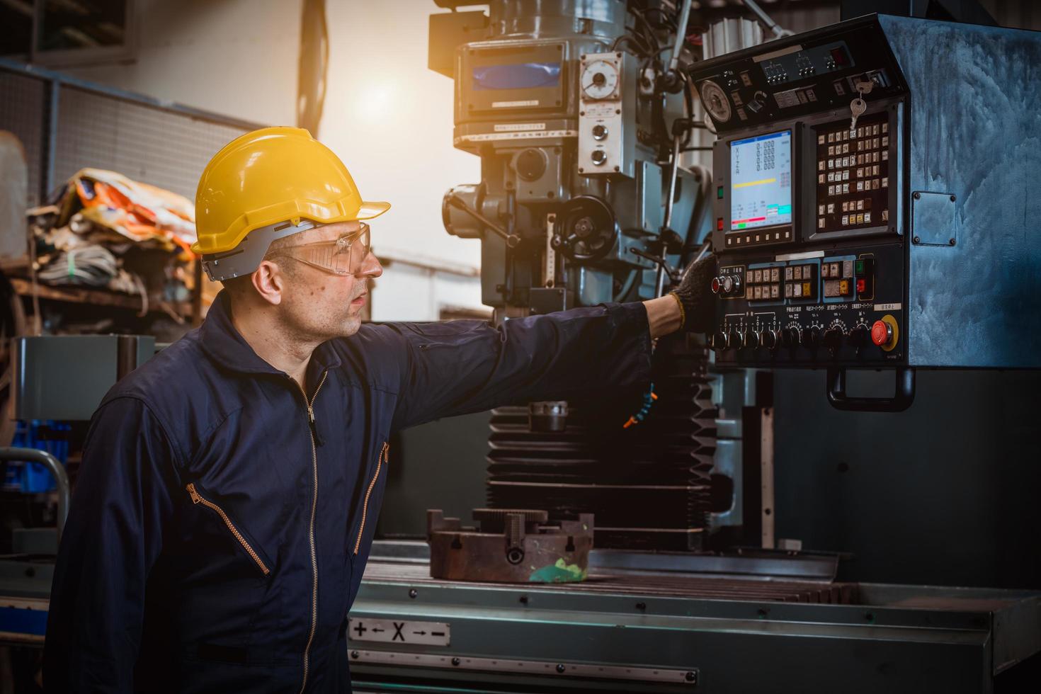 engenharia da indústria vestindo controle uniforme de segurança operando máquina de moagem de torno controlada por computador trabalhando na fábrica da indústria. foto