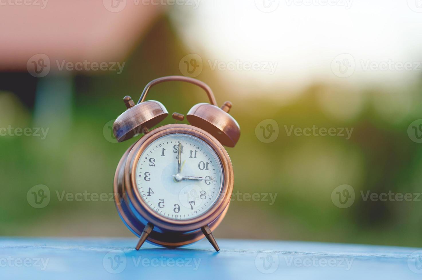 imagem de despertador dourado colocada em uma mesa azul, conceito pontual de fundo verde com espaço de cópia foto