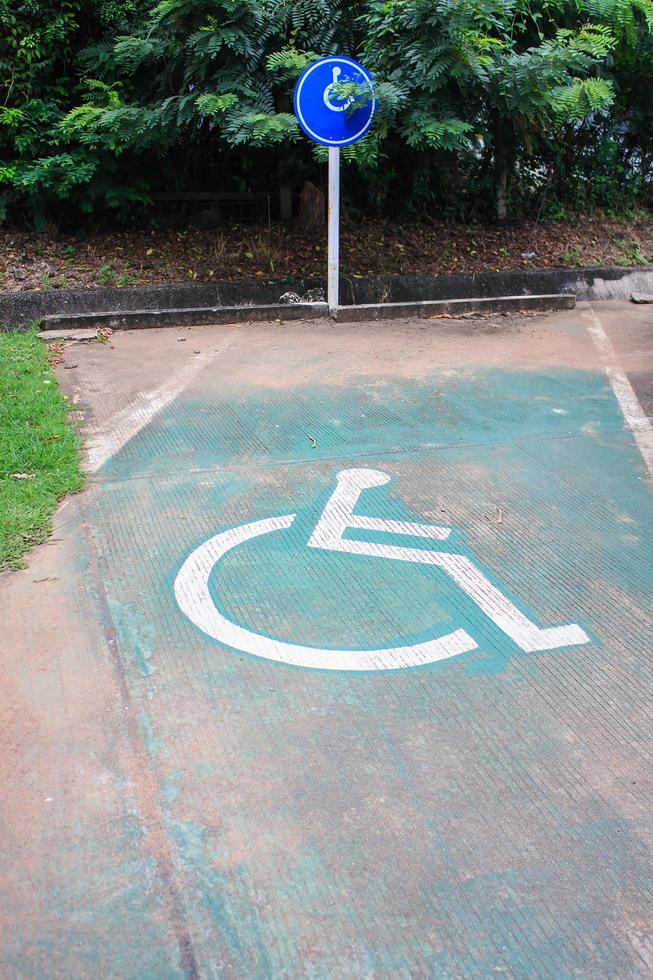 espaço de estacionamento reservado para deficientes na estrada com sinal de deficiente foto