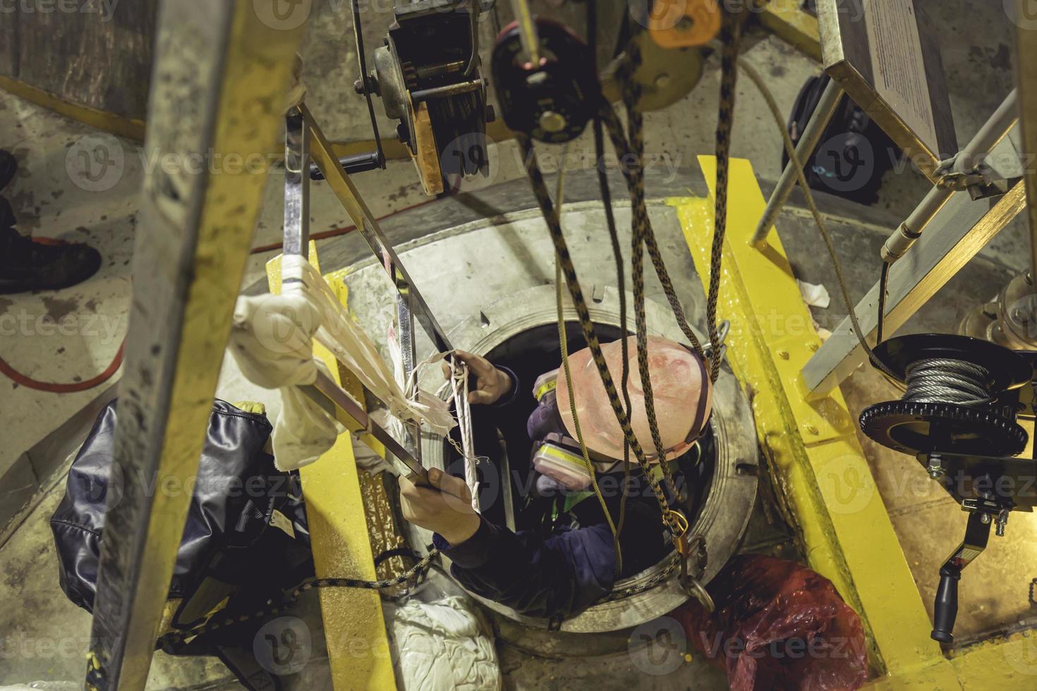 vista superior masculina subir as escadas para o tanque área química inoxidável espaço confinado salvar vidas com corda de resgate foto