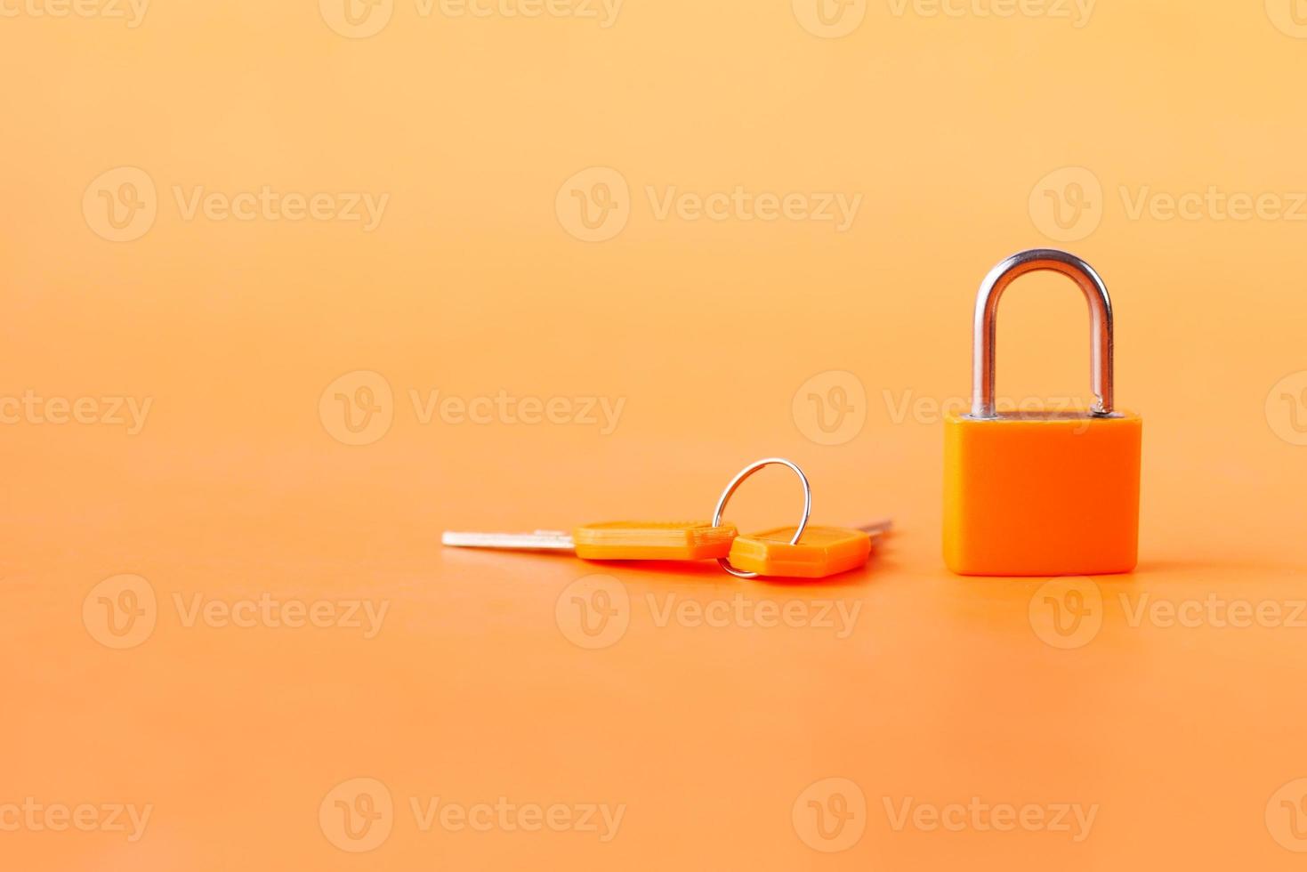 cadeado de cor laranja e chave em fundo laranja foto