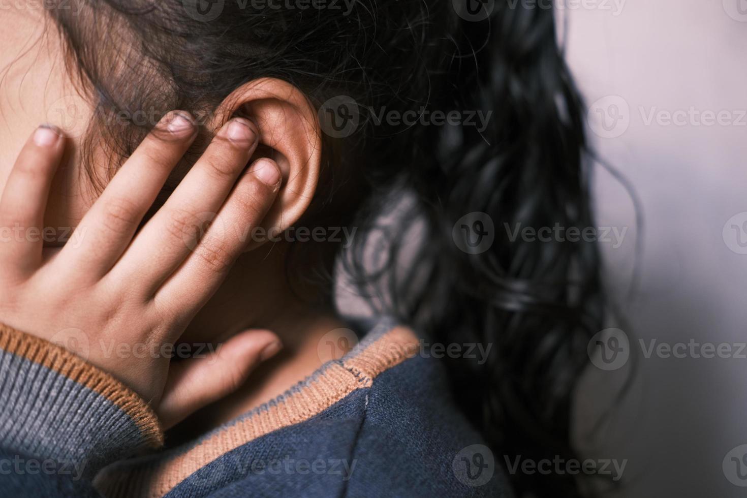 menina criança com dor de ouvido tocando sua orelha dolorosa, foto