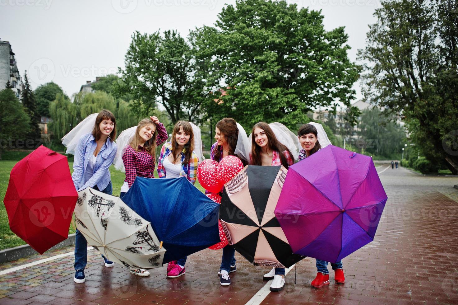 grupo de seis meninas se divertindo na festa de galinha, com guarda-chuva sob chuva e balões. foto