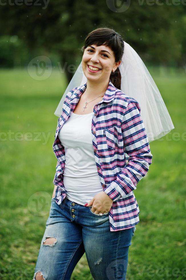 retrato de menina morena na camisa quadriculada, jeans e véu na festa de despedida. foto