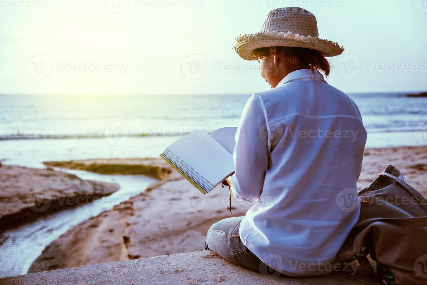 mulher asiática viaja natureza. viajar relaxar estudar ler um livro e escrever uma nota na praia. no verão. tailândia foto