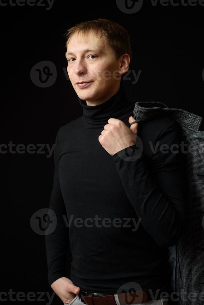 retrato de determinado homem bonito vestindo camisa preta, fundo preto. foto